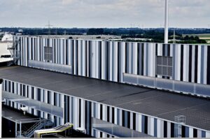 Luftaufnahme des grossen Industriedachs mit Windkraftanlagen im Hintergrund, Referenzprojekt Aluminiumwerk Grevenbroich von HDG Dachtechnik