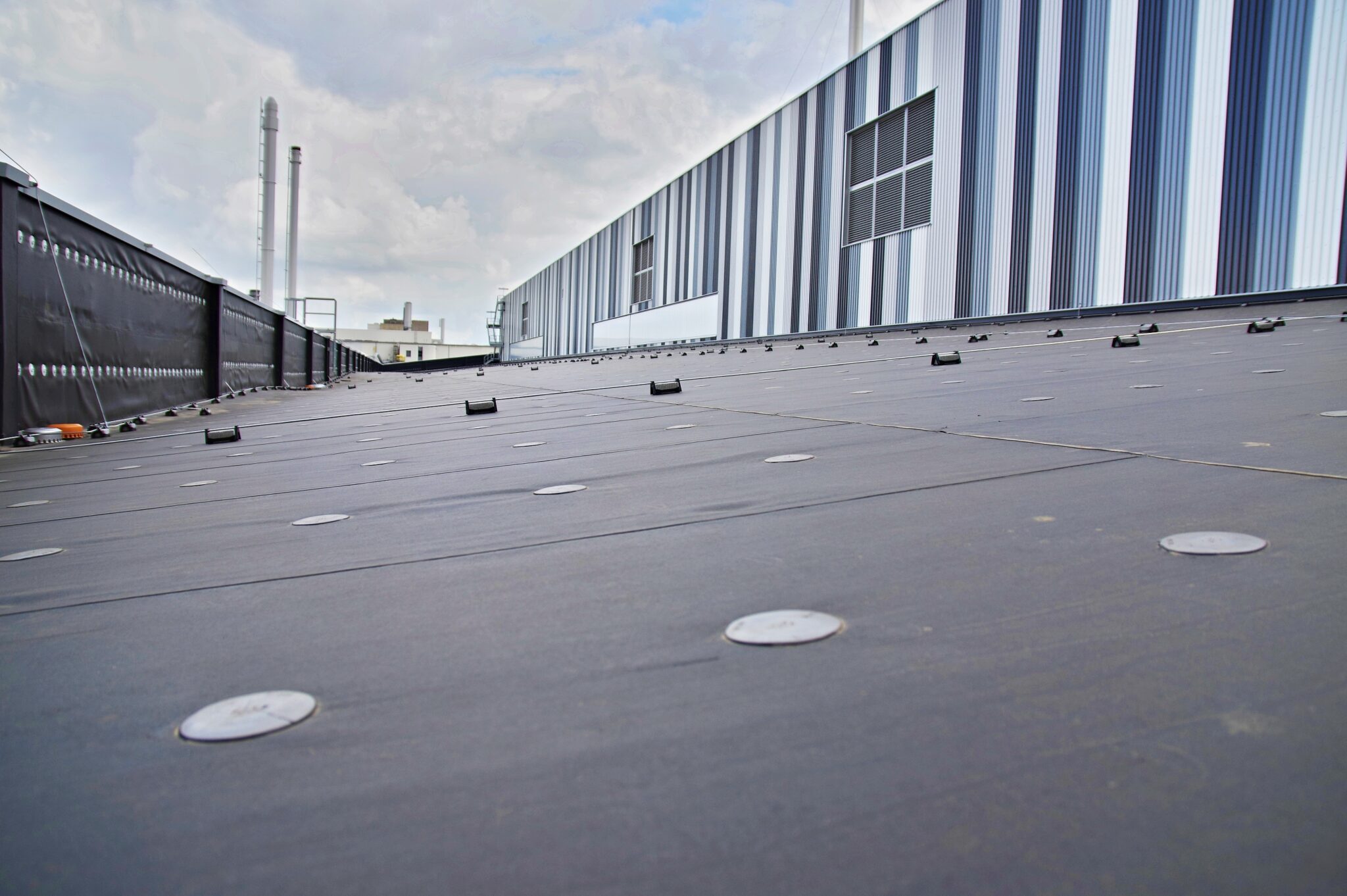 Neu abgedichtetes Flachdach mit Industriegebaeude im Hintergrund, Referenzprojekt Aluminiumwerk Grevenbroich von HDG Dachtechnik
