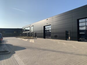 Eingangsbereich des DT Swiss Firmengebaeudes mit dunkler Fassade und Flachdach, Referenzprojekt von HDG Dachtechnik