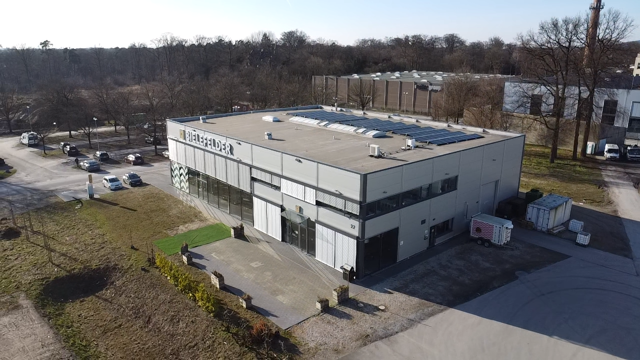 Luftaufnahme des gesamten Firmengebaeudes mit Photovoltaikanlage auf dem Flachdach, Referenzprojekt von HDG Dachtechnik