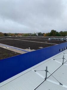 Flachdach mit blauer Attikaverkleidung aus Trapezblech, Referenzprojekt von HDG Dachtechnik