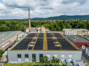 Luftaufnahme des begruenten Flachdachs mit Photovoltaikanlage und Industriegebaeude, Referenzprojekt Moeller Real Estate von HDG Dachtechnik