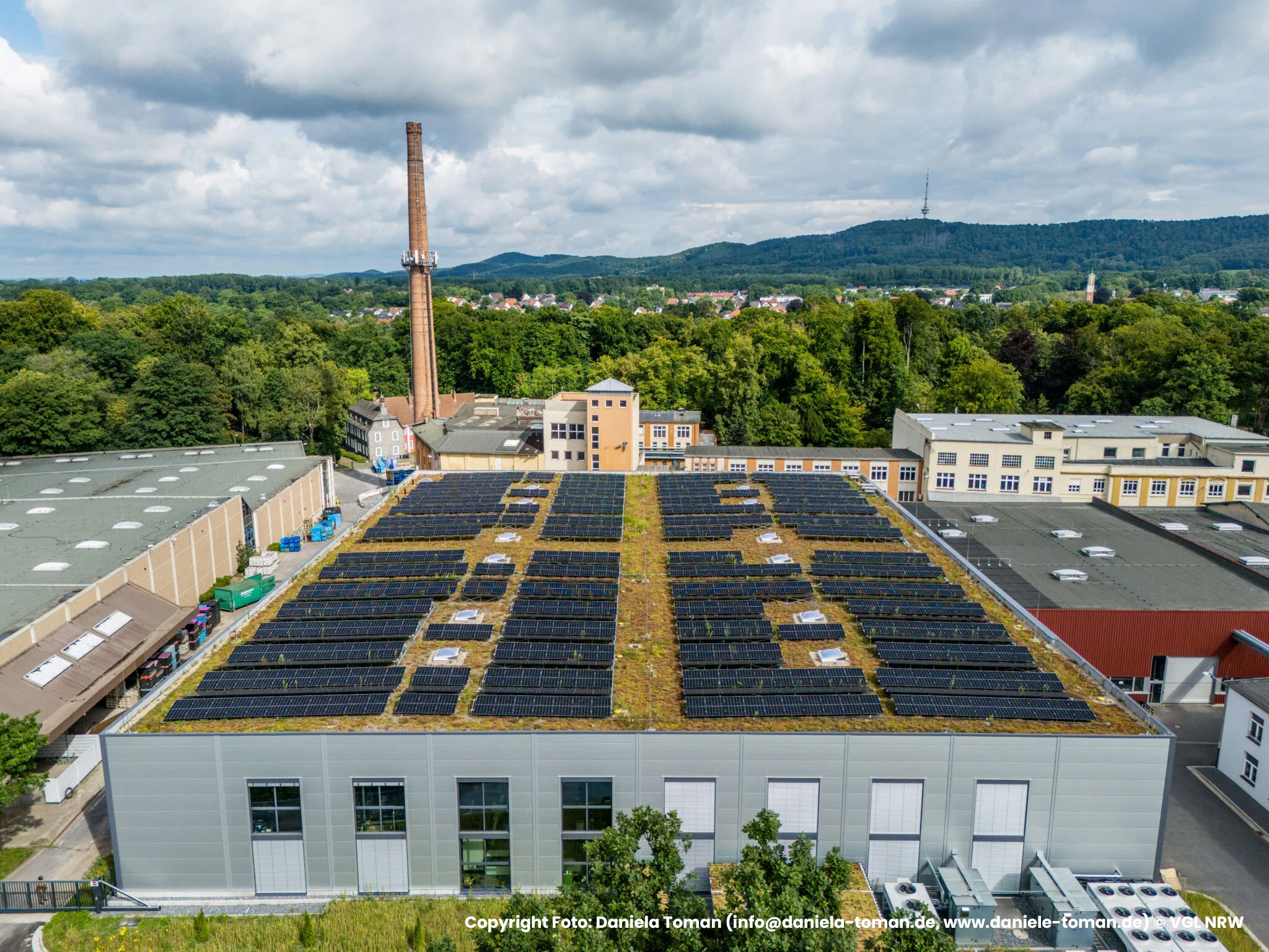 Luftaufnahme des begruenten Flachdachs mit Photovoltaikanlage und Industriegebaeude, Referenzprojekt Moeller Real Estate von HDG Dachtechnik